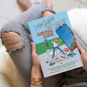 A parent holding the Mothers of Boys Survival Guide-book.