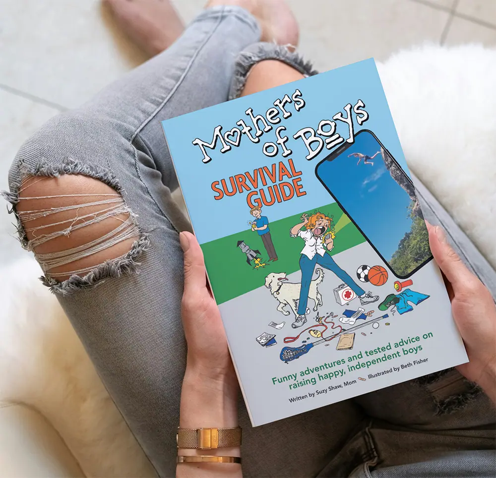 Mothers of Boys Survival Guide-book A parent holding the Mothers of Boys Survival Guide-book.